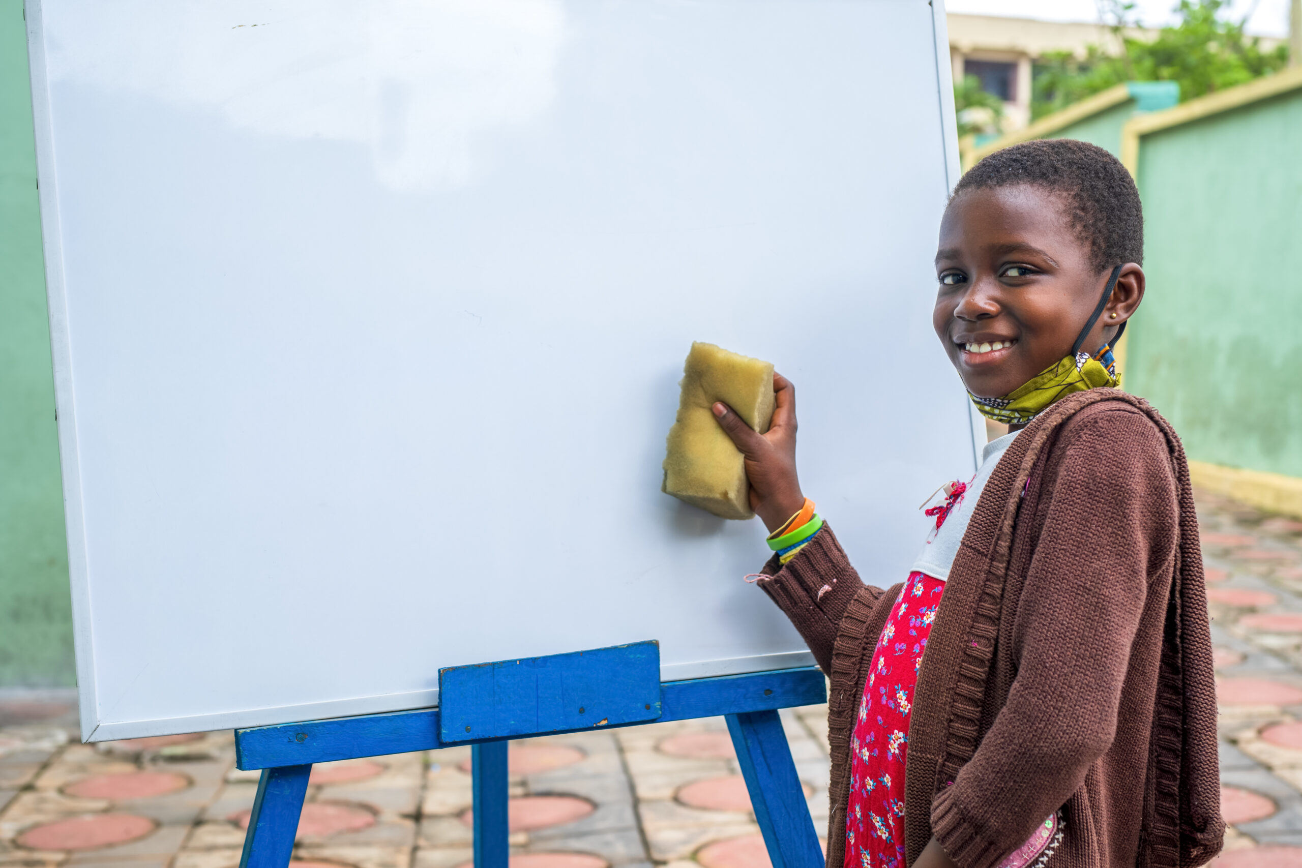 A closeup shot of a black male child erasing a whiteboard - education concept